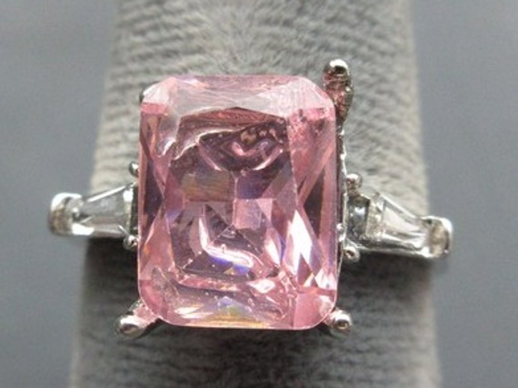 Unmarked silver-tone ring with pink emerald-cut stone and clear baguettes