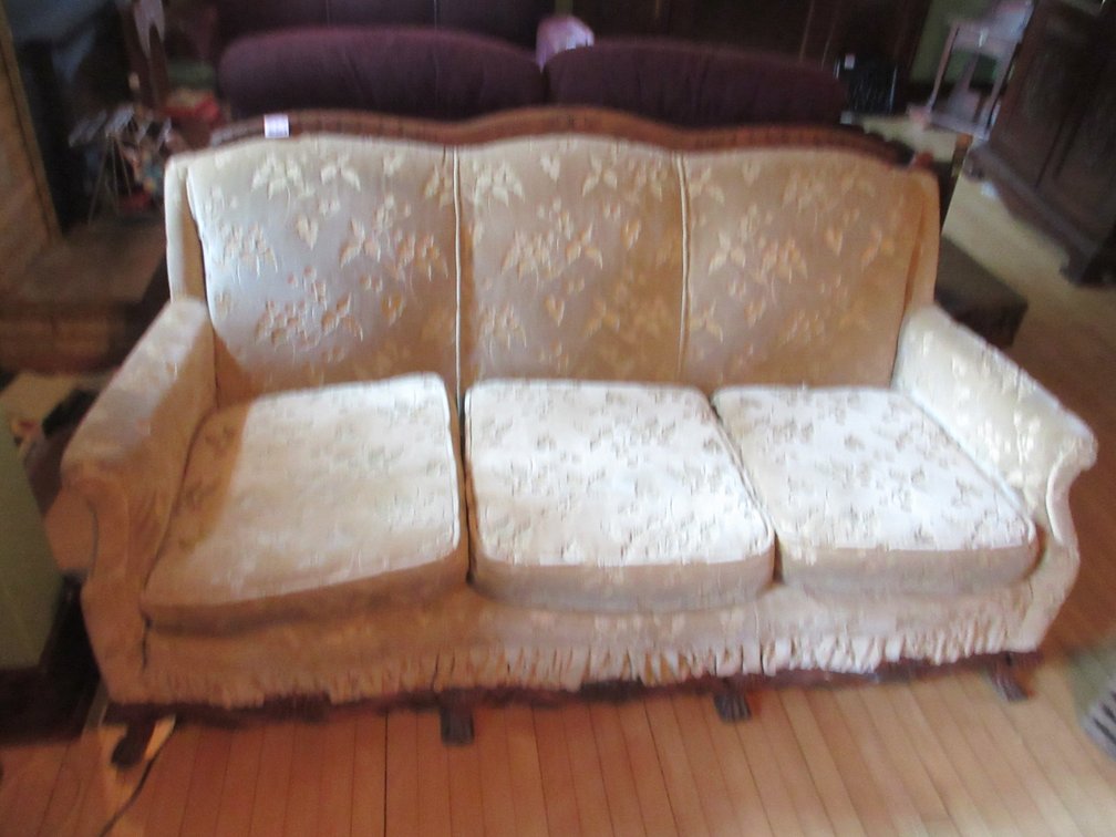 Antique upholstered sofa with wood detail and leaf/floral pattern