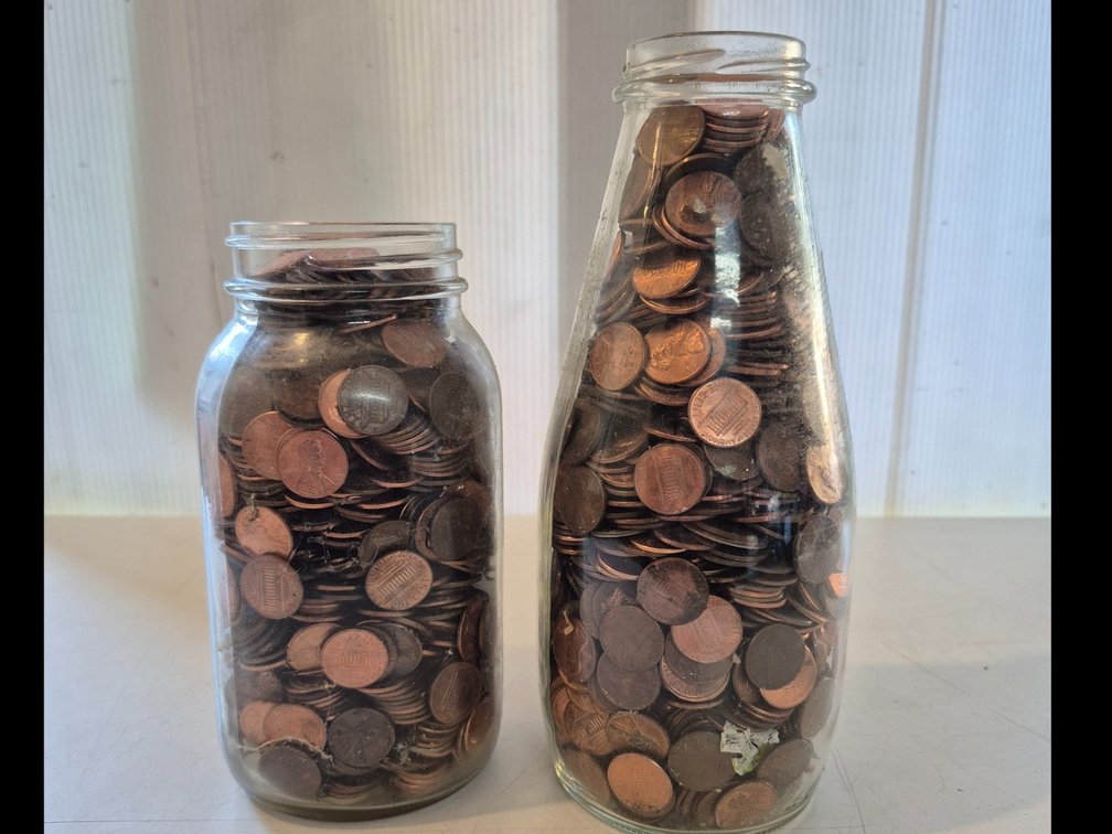 Jar and bottle full of unsorted pennies