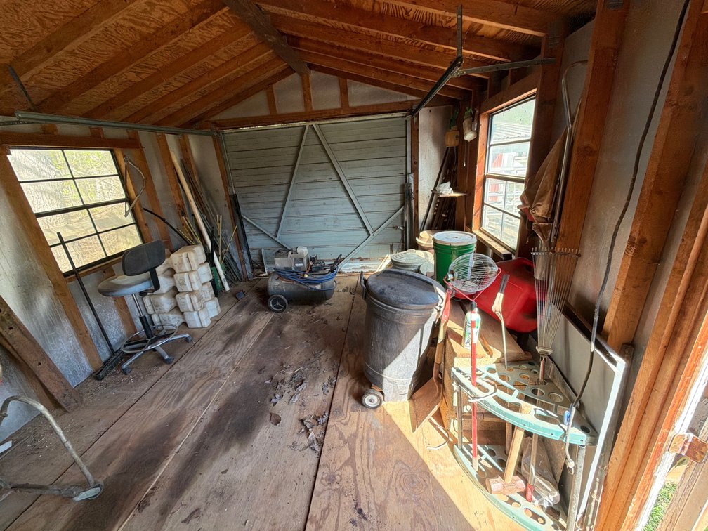 Shed lot with trash cans (feed inside), air compressor, metal stakes, etc