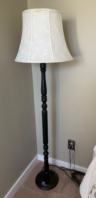 A traditional black turned-wood or metal floor lamp with a flared white fabric shade