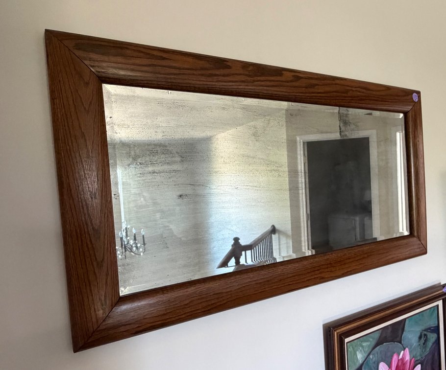 rectangular wall mirror with a thick warm-toned solid wood frame and a beveled glass plate