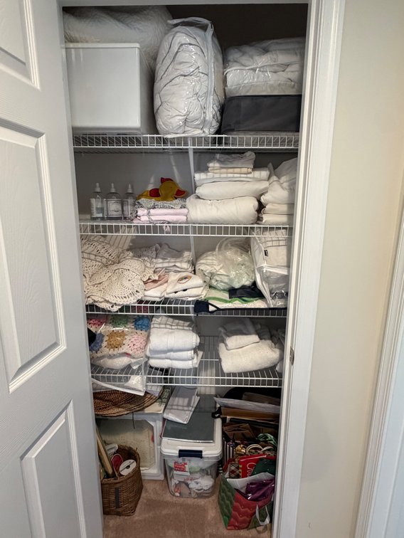 Hallway closet contents includes sheets, comforters, blankets, gift wrapping bags, etc