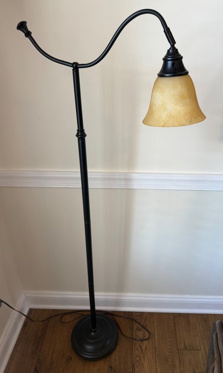 A black metal floor lamp featuring a gooseneck arm and a bell-shaped amber-tinted glass shade
