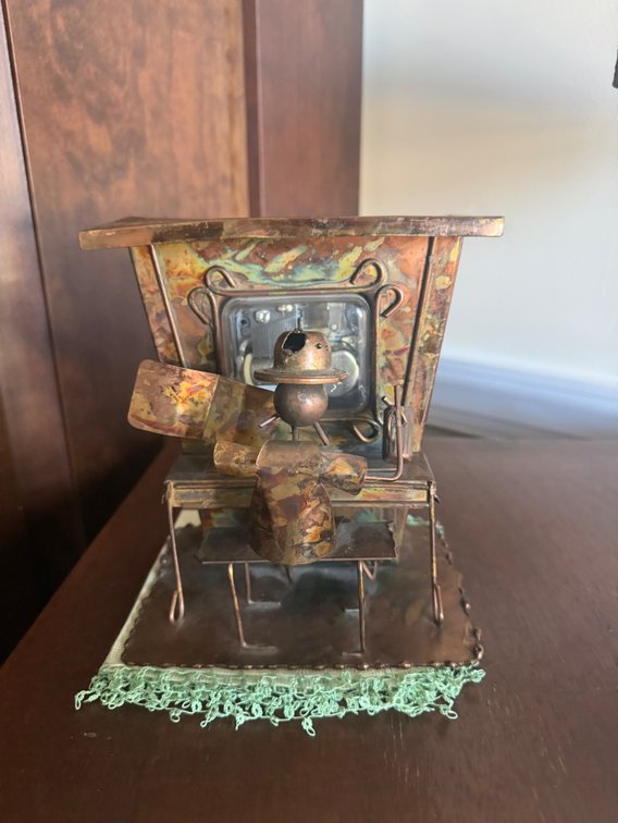 A vintage 1970s copper-toned metal art wind-up music box featuring a saloon piano player in a flat hat