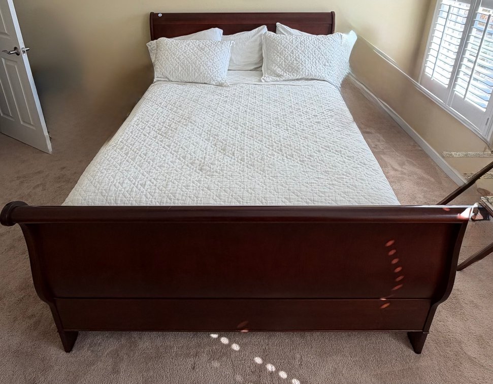 Traditional wood sleigh bed frame with a rich cherry finish including white diamond-quilted pillows and bed top comforter