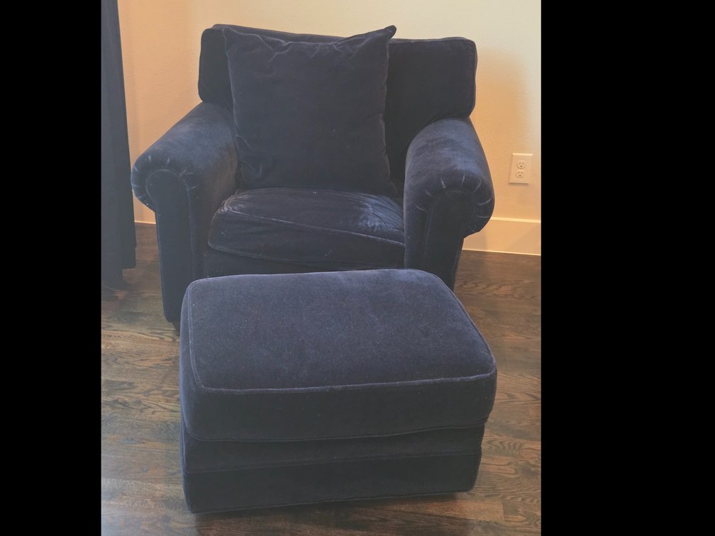 Deep navy blue plush velvet armchair with a matching ottoman and accent pillow