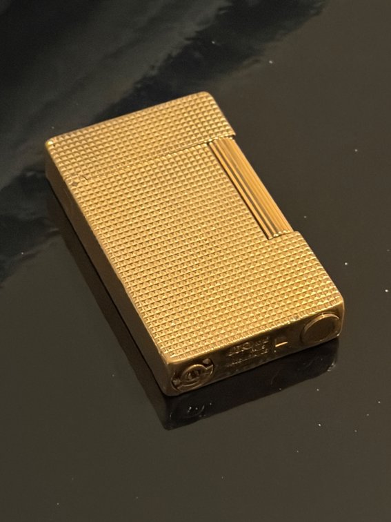 vintage S.T. Dupont Ligne 1 or similar luxury gold-plated pocket lighter featuring a textured diamond-head or grain pattern.