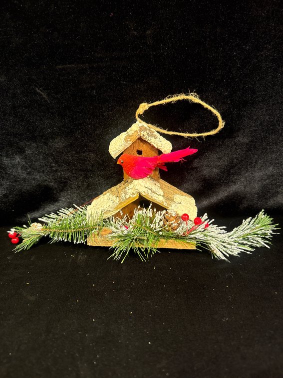 rustic wooden holiday ornament featuring a snow-dusted A-frame birdhouse, a red cardinal perched near the entrance