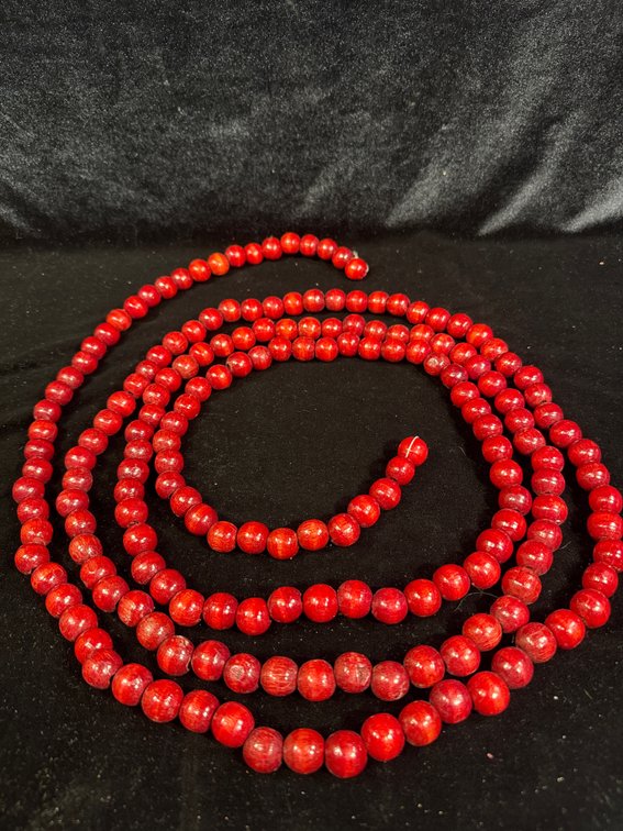 long strand of red round beads that appear to be red coral beads (or coral-style gemstone/glass beads)