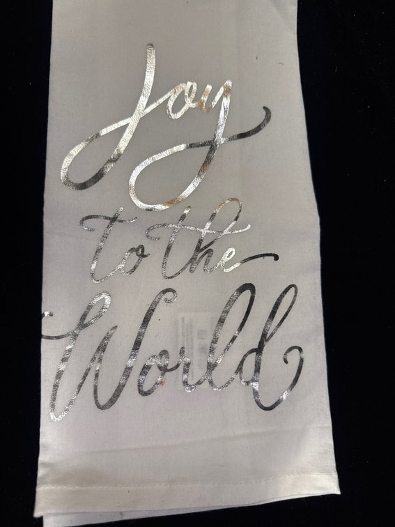 white decorative kitchen dish towel featuring the cursive holiday phrase "Joy to the World" in metallic script