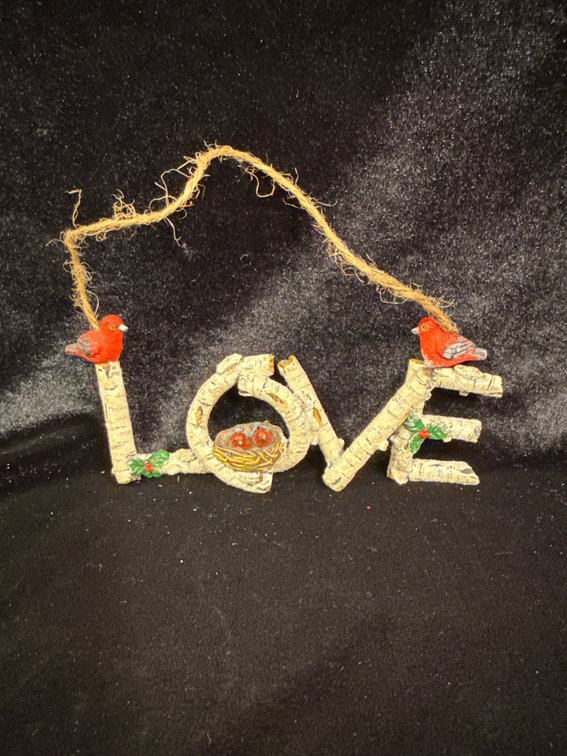 rustic LOVE word ornament made to look like birch tree branches, accented with a cozy nest in the "O" and red cardinal birds perched on the ends