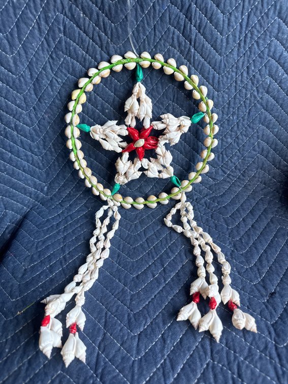 shell-crafted parol (a traditional Filipino Christmas star lantern) or seashell wall hanging/wind chime made from natural and dyed shells arranged into a star-in-circle design with hanging strands