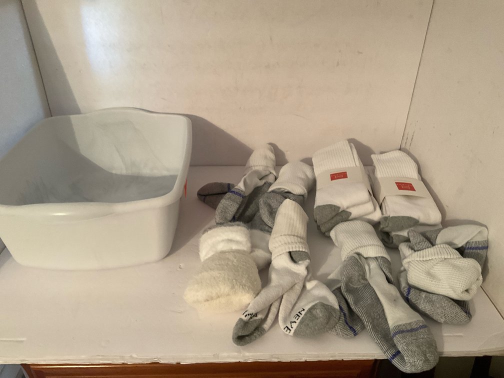 Assorted Hanes & Neveno crew socks with plastic tub