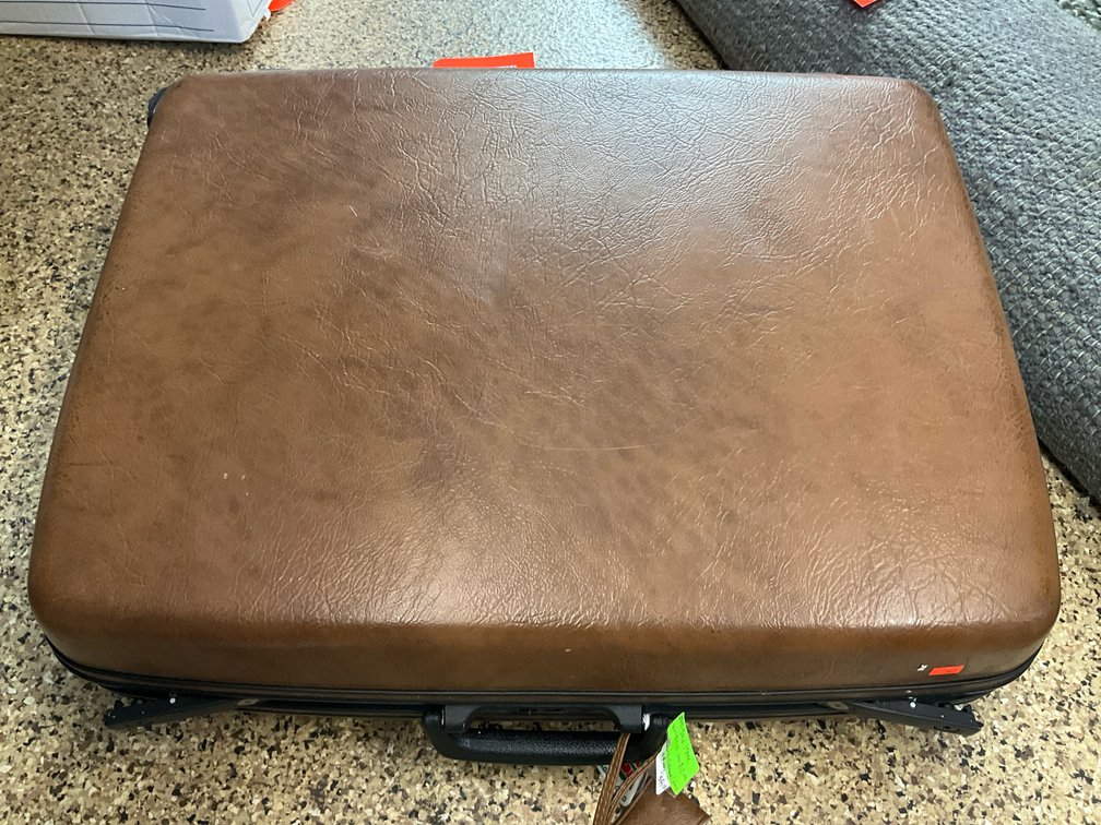 Brown textured hard-sided suitcase with luggage tag