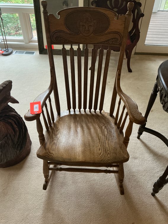 Oak pressed-back rocking chair with stylized face crest - Den Main Level