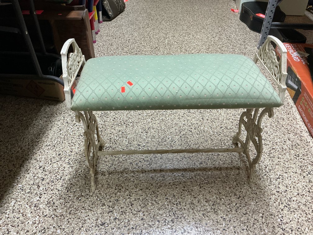 Painted cast metal bench with green upholstered seat