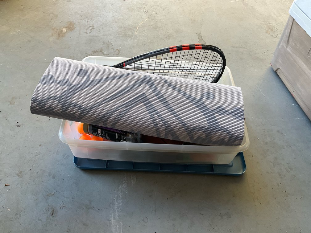 Sporting goods lot with footballs, racquet & mat - Garage
