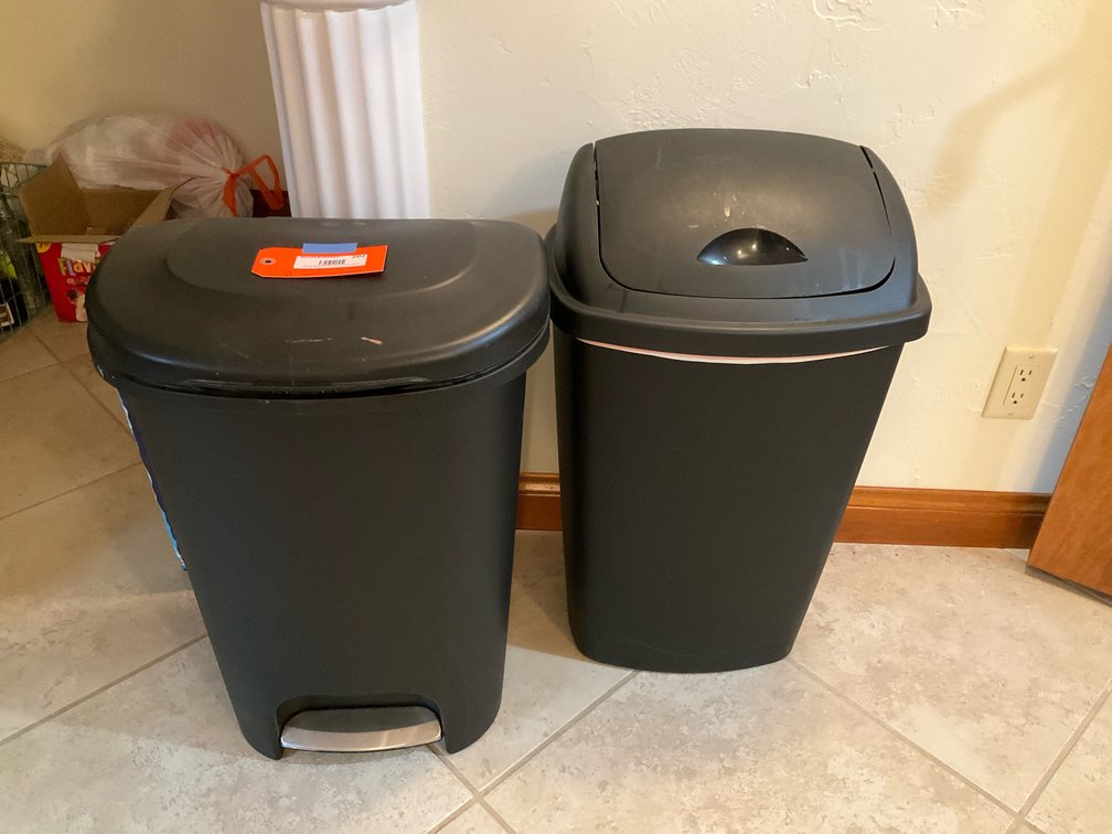 Pair of black plastic step-on & swing-top trash cans - Basement Living & Bar Area