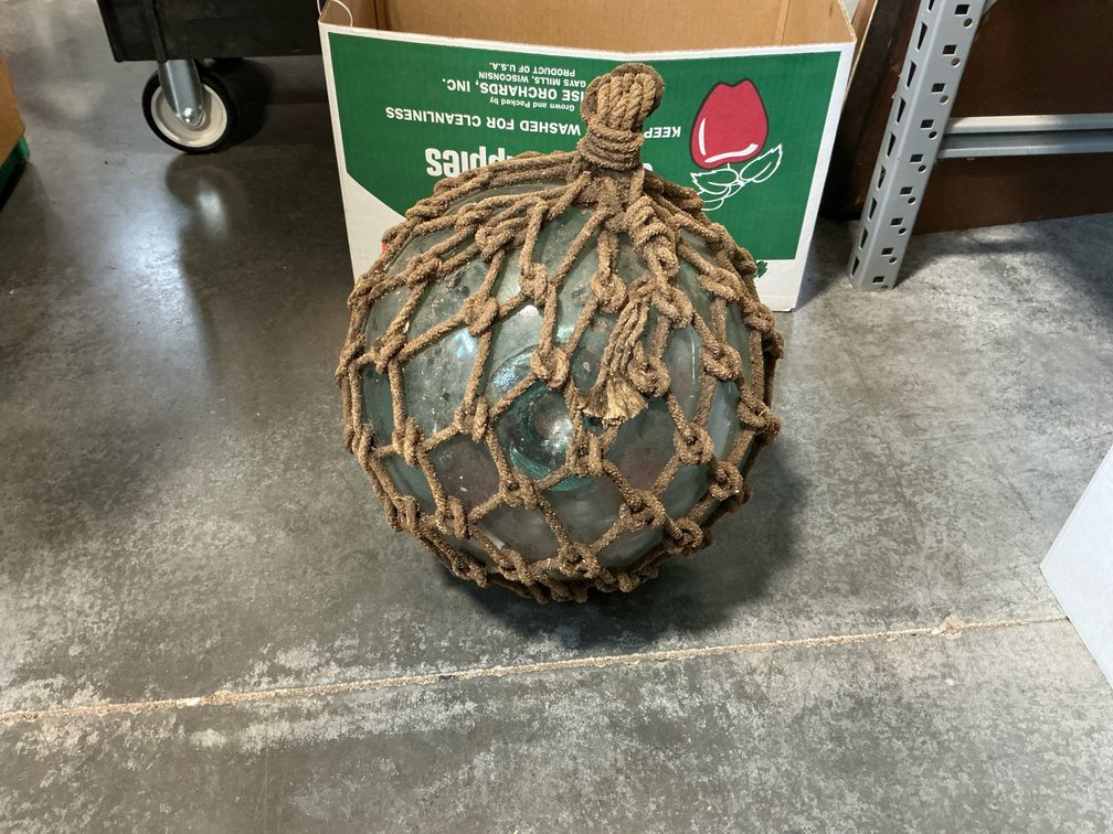 Aqua-green glass fishing float in rope netting