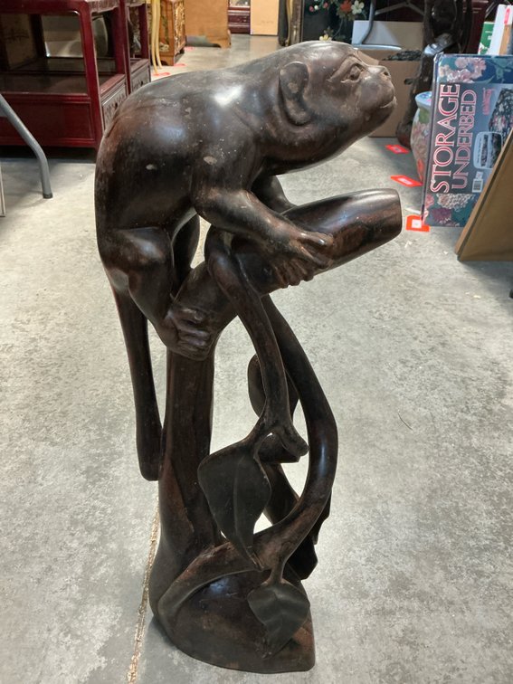 Carved dark wood monkey sculpture on branch
