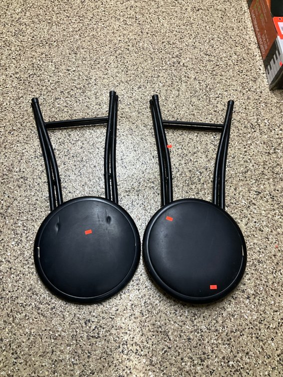 Pair of black folding stools with padded vinyl seats