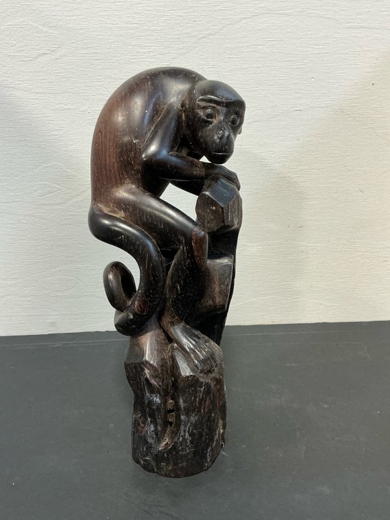 Carved dark wood monkey figurine on stump