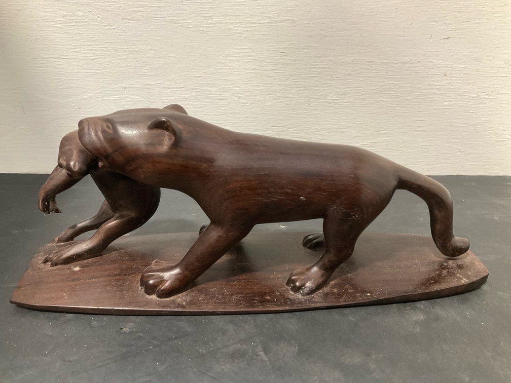 Carved dark wood predatory cat sculpture with prey