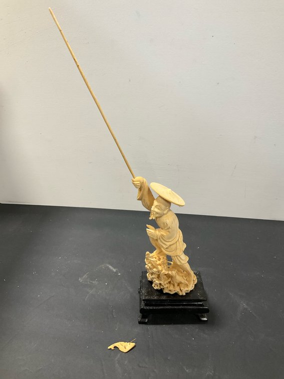 Carved fisherman figurine on wooden stand