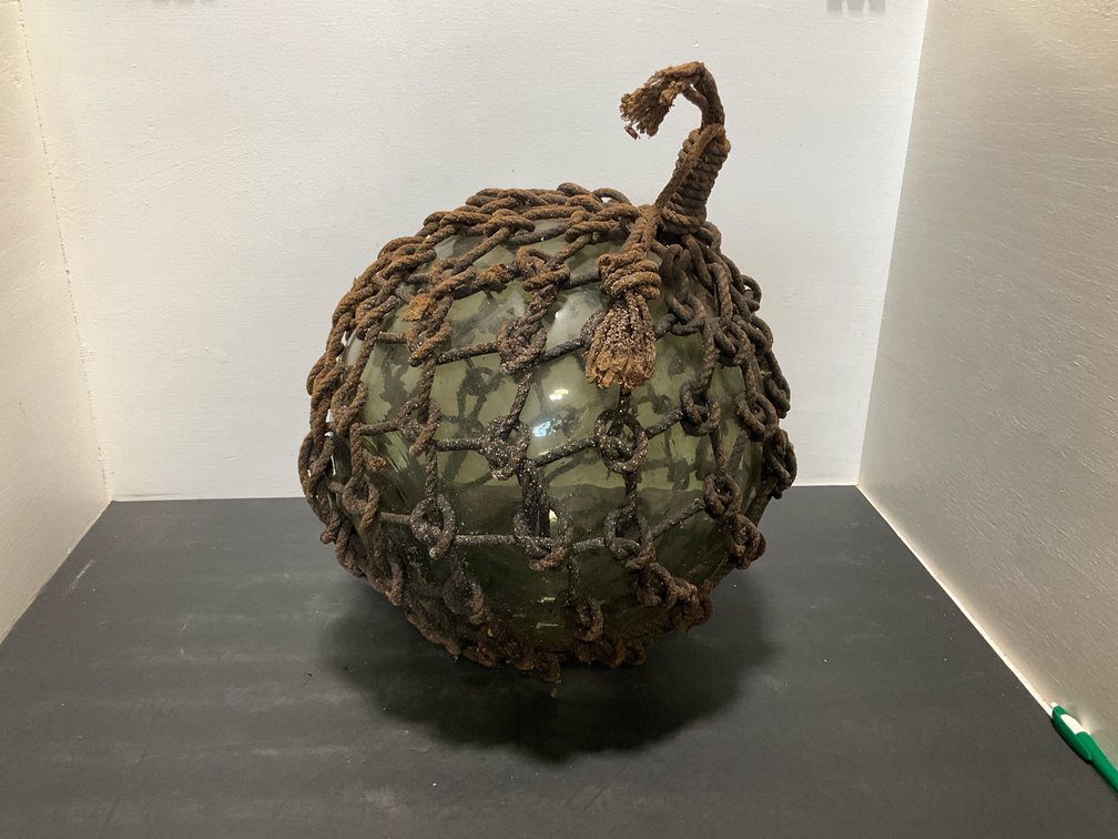 Green glass fishing float in rope netting