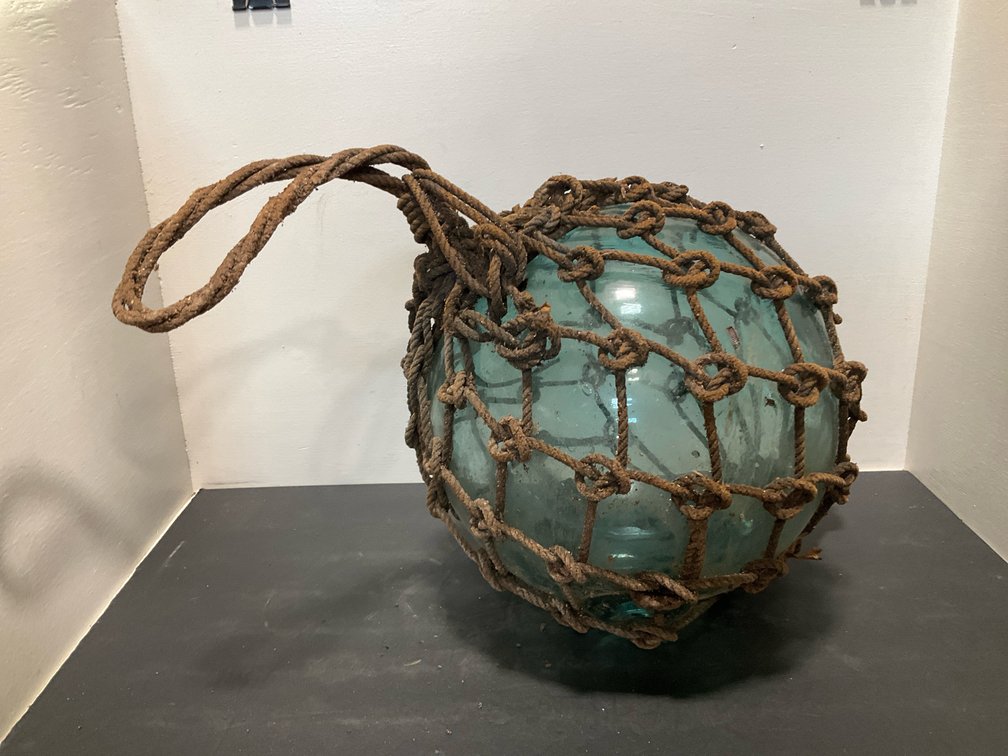 Aqua glass fishing float in knotted rope netting