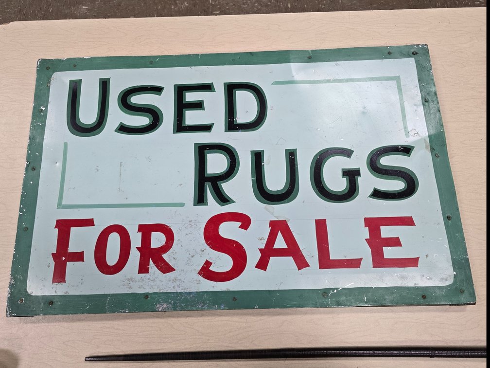 Double-sided "Used Rugs For Sale" sign.
