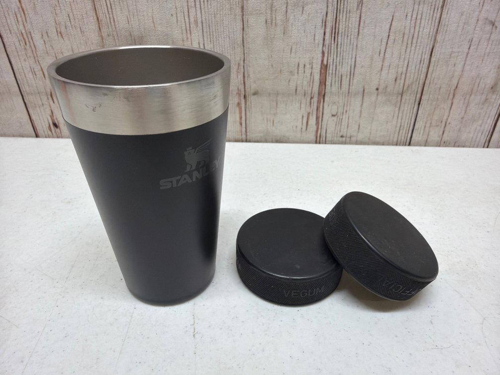 Stanley coffee cup and 2 hockey pucks