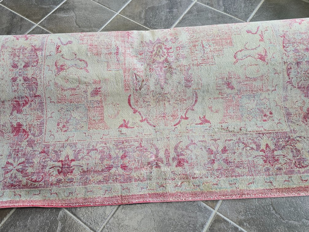 Area rug in pink and cream with faded design