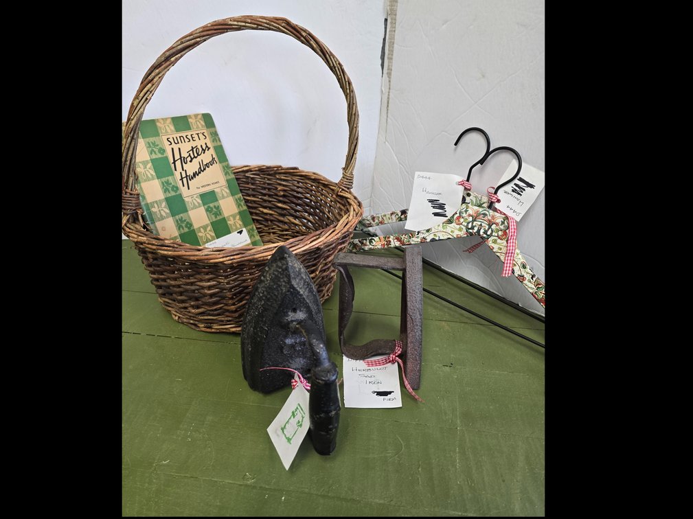 Two sad irons, basket and hostess handbook and two hangers