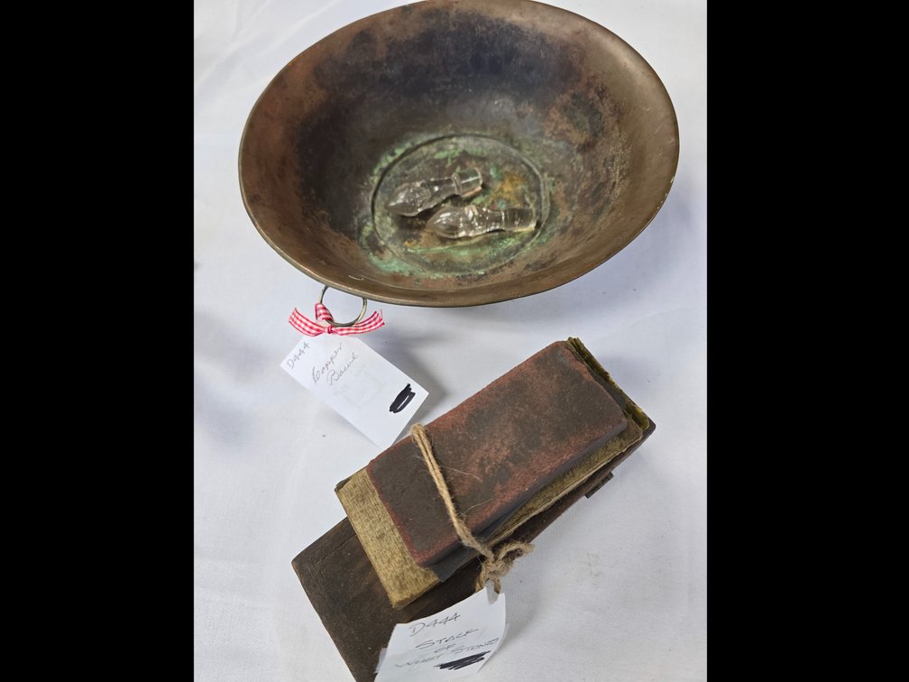 Copper bowl with two vinegar cruets stoppers and a stack of whet stoness