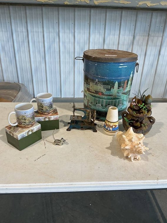 This Lot Includes a Holiday tin Bucket with Sea Shell. Southwestern vase , mini dog paper weight, mini hand crank swinging machine, frog water decoration and two unused coffee mugs