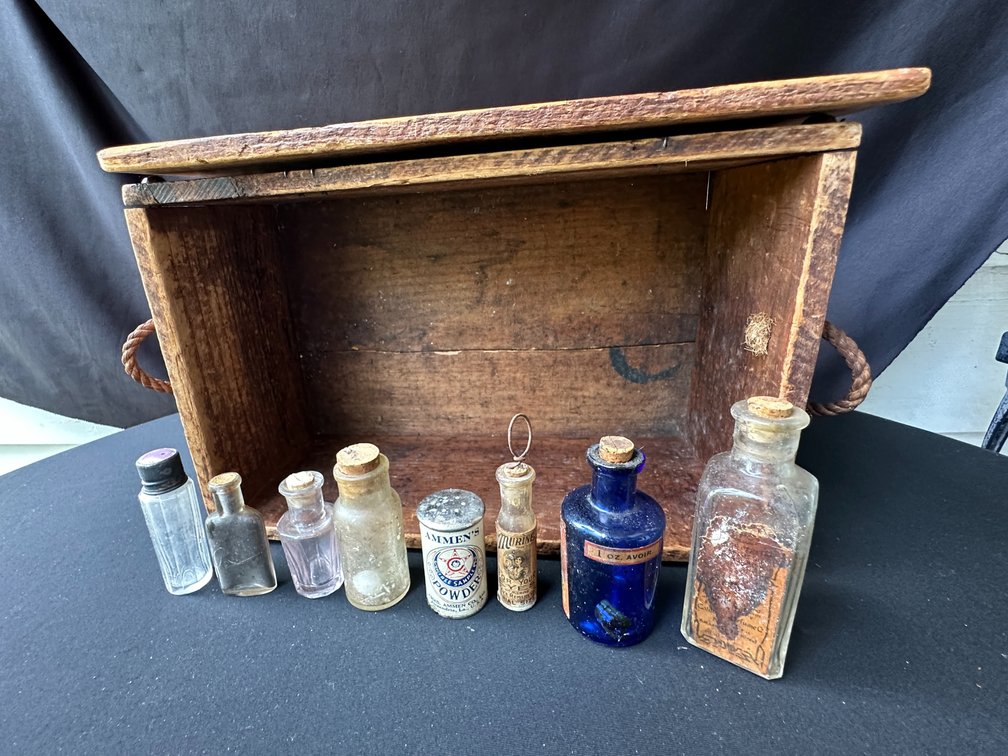 Wooden Crate with Rope Handles, Glass Bottles, and Tin