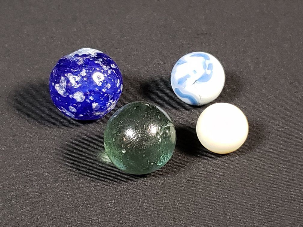 Four Glass Marbles Including Cobalt, Swirl, and Green Glass