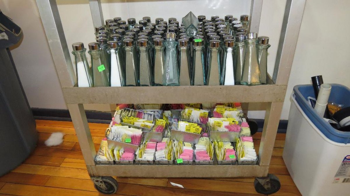 Group of salt and pepper shakers and table condiment trays. Cart is sold separately