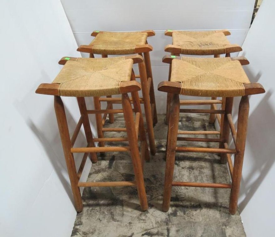 A set of four wooden bar stools with rush seats. Shows wear.