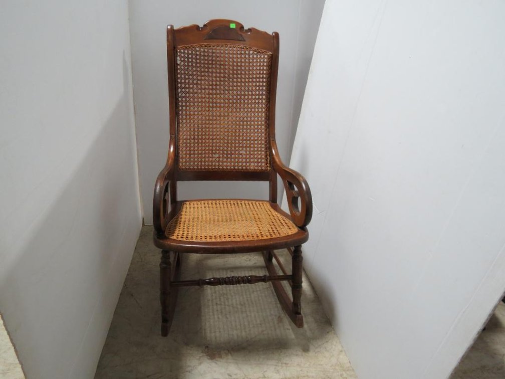 A vintage wooden rocking chair with caned back and seat.