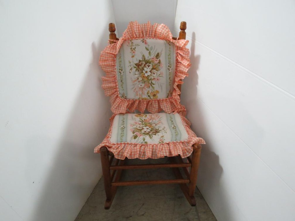 A vintage child�s rocking chair with woven seat and chair covers.