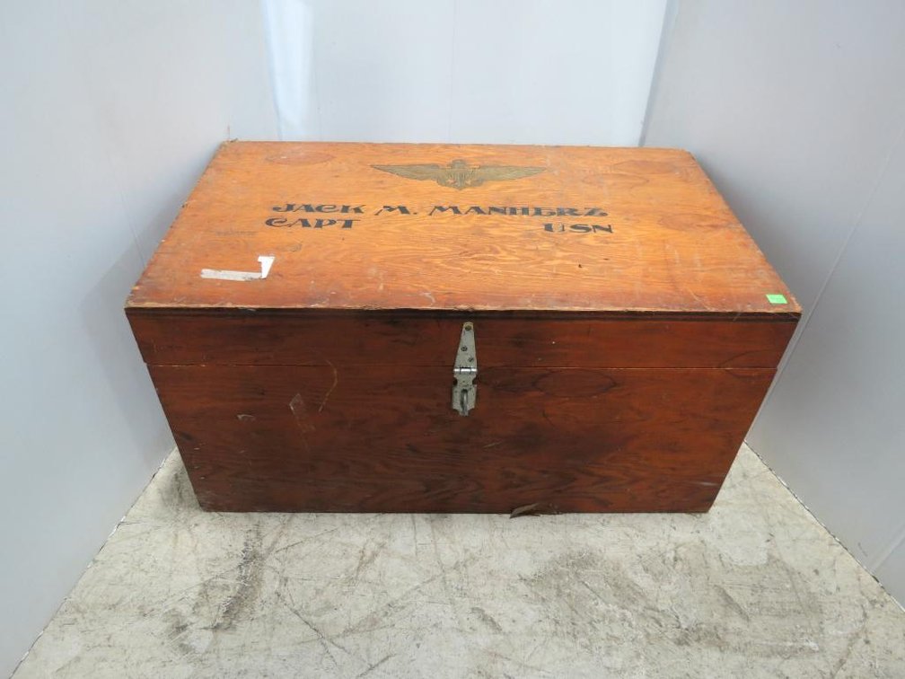 A vintage wood military trunk with USN and Captain Jack M. Manherz painted on the top.