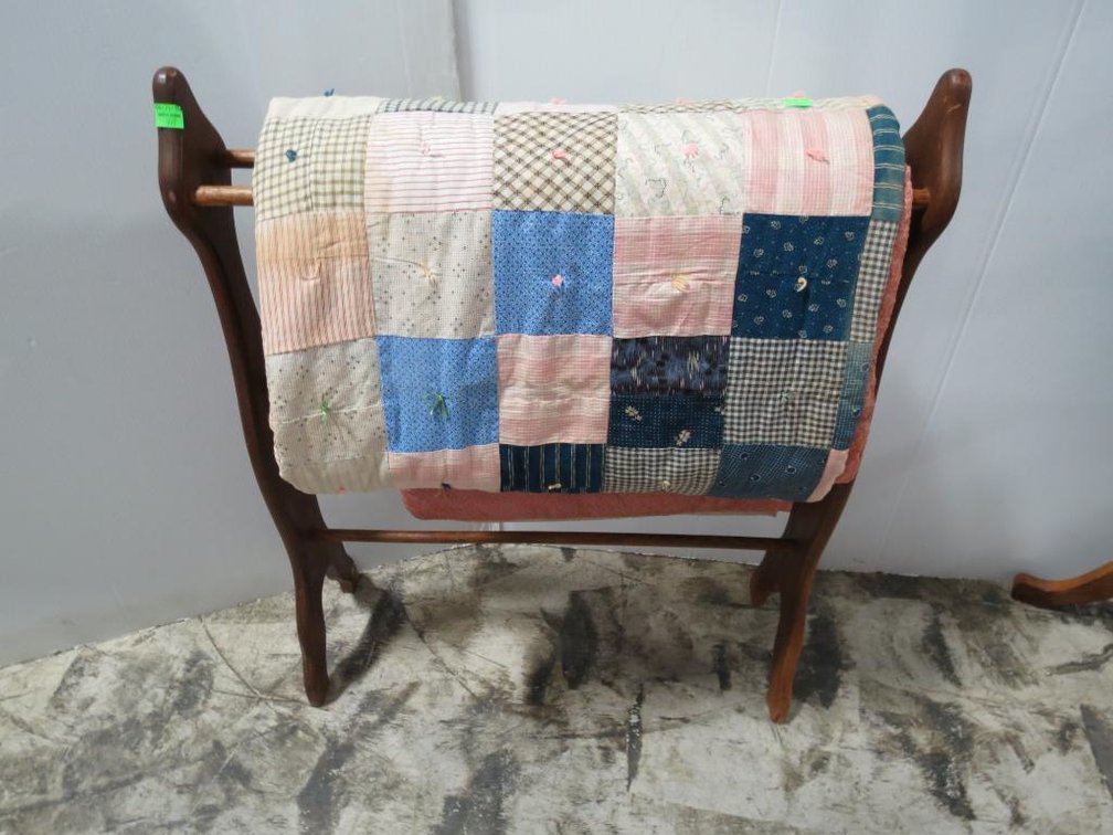 A vintage quilt stand with a handmade quilt.