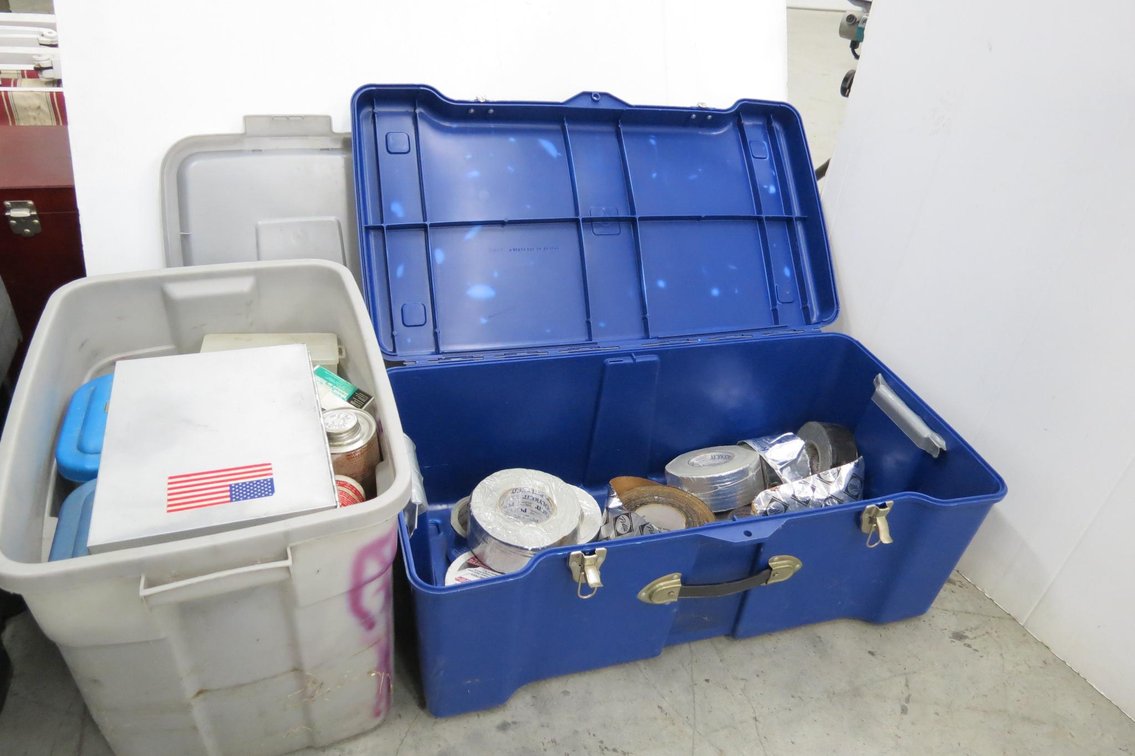 Plastic Totes With Plumbing Supplies and Rolls of Tape