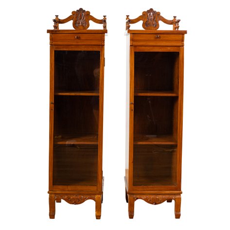 A pair of Art Nouveau escaparates de rinconera (corner display cabinets) with carved family monogram within a lyre crest