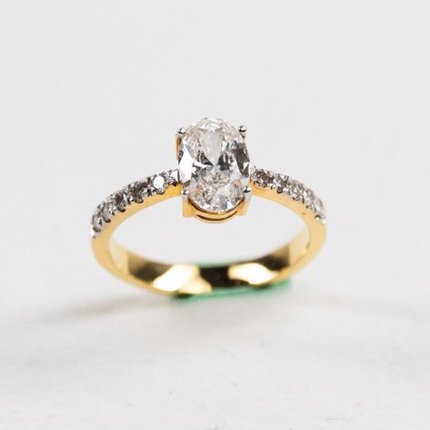 An oval-shaped solo ring with diamonds in 14k yellow gold