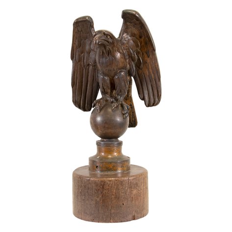 A majestic decorative bald eagle sculpture in powerful stance with semi-outstretched wings atop a globe