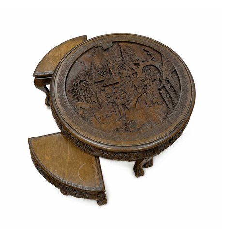 A nesting tea table deeply carved with imperial palace scenes, with four modular quadrant stools